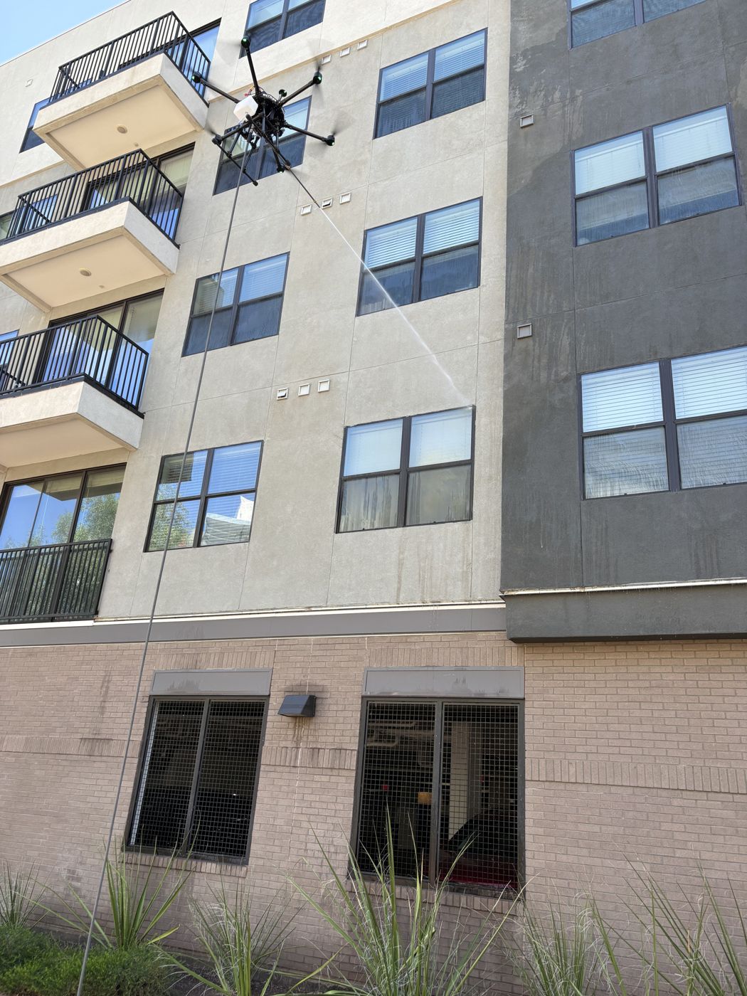 Drone soft washing an apartment building